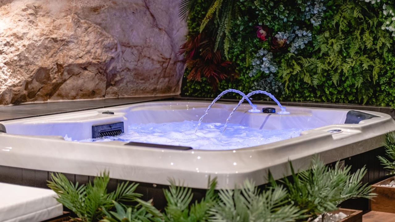 Jacuzzi s plavim osvjetljenjem uz zeleni zid